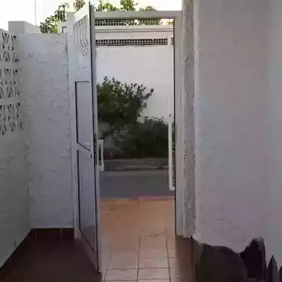 Portail métallique blanc entrouvert donnant sur une cour