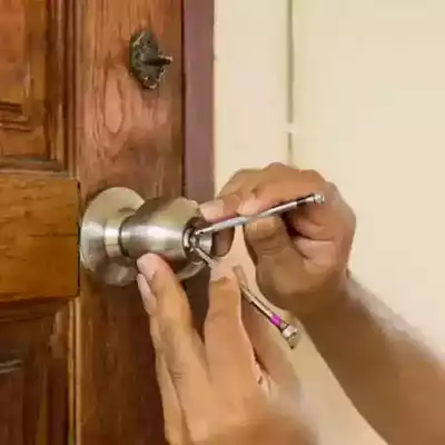 Main d’un serrurier manipulant une poignée de porte claquée