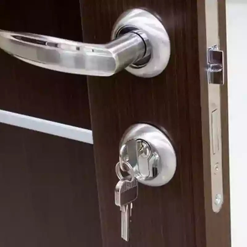 Clés pendantes sur une serrure verrouillée d’une porte en bois foncé