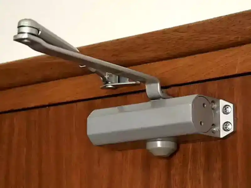 Mécanisme de ferme-porte hydraulique installé sur porte d'immeuble